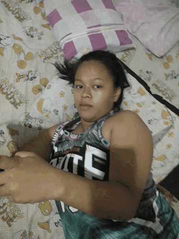 a girl laying on a bed with a mickey mouse blanket on it