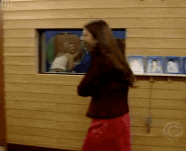 a woman in a red skirt is standing in front of a wooden wall ..
