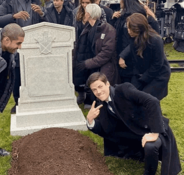 a group of people standing around a gravestone with a cross on it