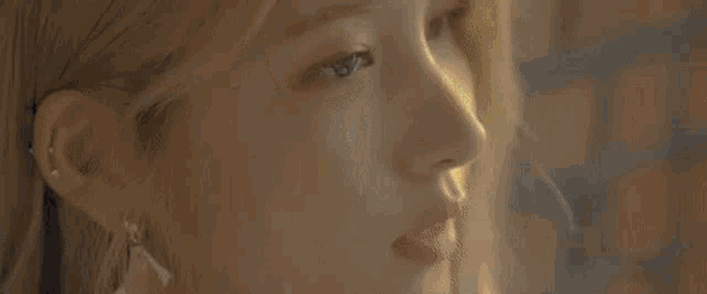a woman is looking out of a window at a sunset