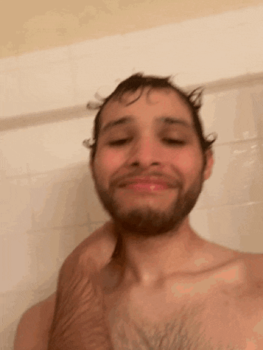 a man with a beard is taking a selfie in the shower .