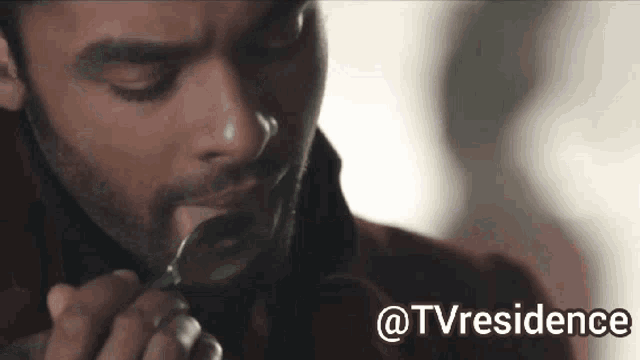 a man is holding a spoon in his mouth while eating something .