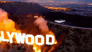 a hollywood sign is on fire with a city in the background