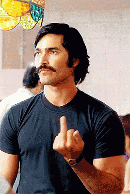 a man with a mustache and a black shirt giving the middle finger