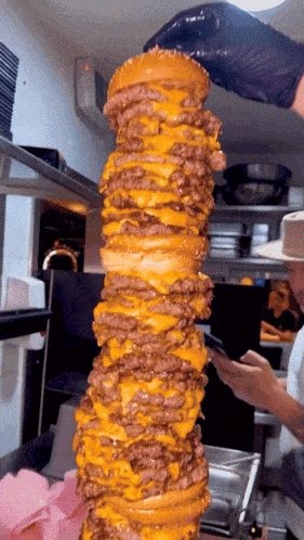 a very tall stack of hamburgers with cheese on top of them