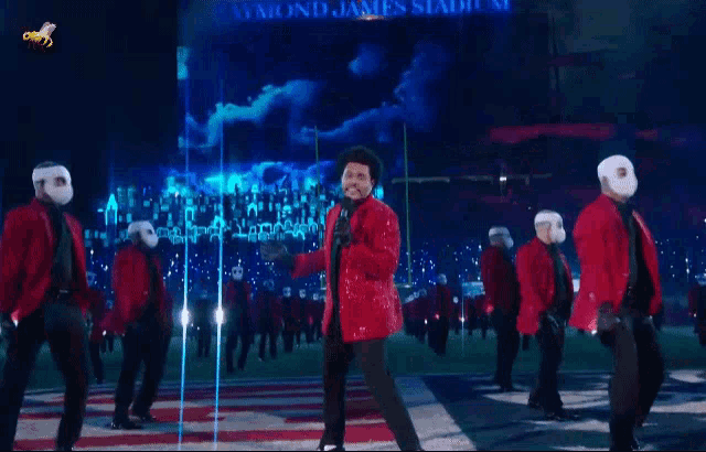 a man in a red jacket stands in front of a microphone