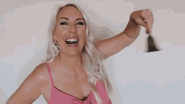 a woman in a pink top is holding a bell and giving a thumbs up .