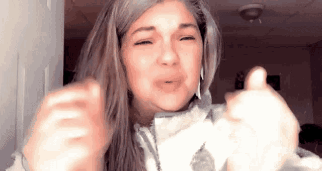 a woman is giving a thumbs up sign with her hands .