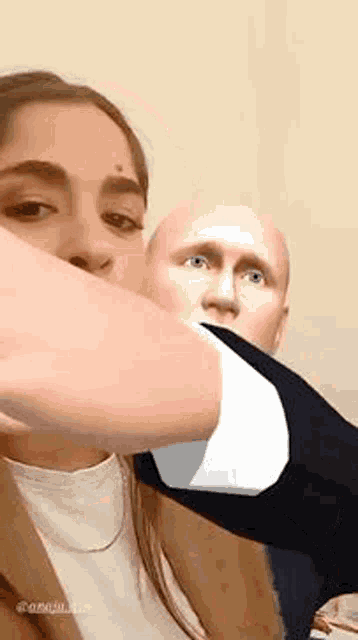 a man and a woman are standing next to each other and the woman is holding the man 's arm in front of her face .