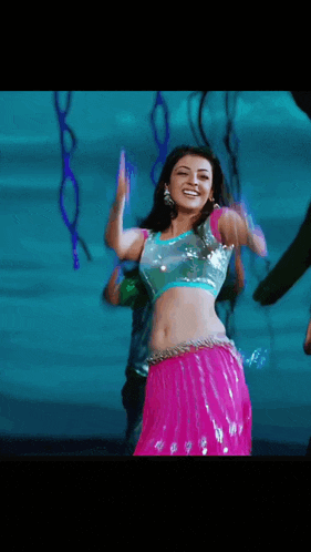 a woman in a pink skirt and a blue top is dancing .