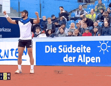 a tennis player stands in front of a blue sign that says die sudseite der alpen