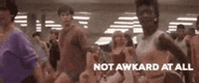 a group of people are dancing in a room with the words `` not awkard at all '' written in the corner .