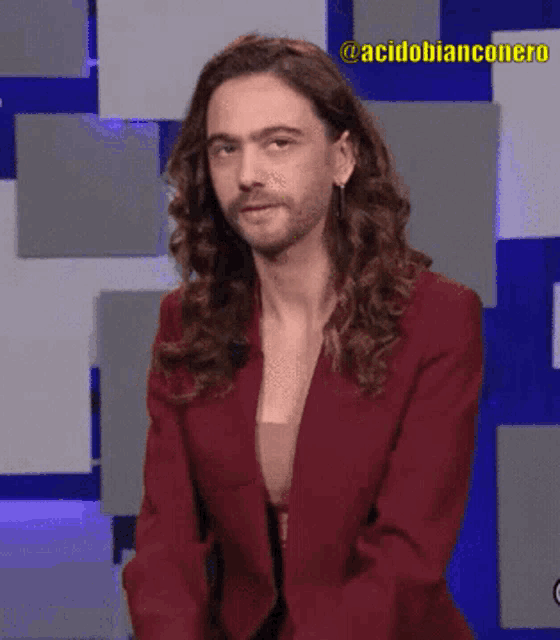 a man with long hair and a beard is wearing a red jacket that says acidobianconero
