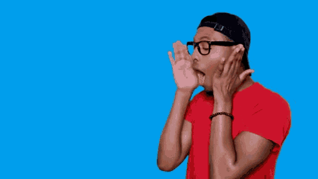 a man wearing glasses and a red shirt is shouting into the air .