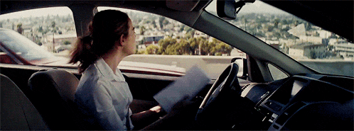 a woman in a white shirt is sitting in a car holding a piece of paper