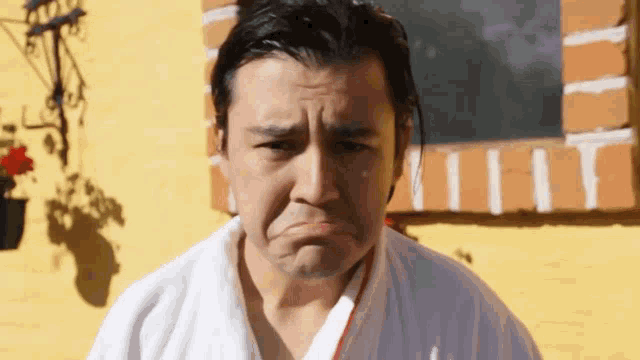 a man with a white towel around his neck making a sad face