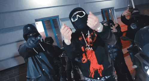 a man wearing a ski mask and goggles giving a thumbs up
