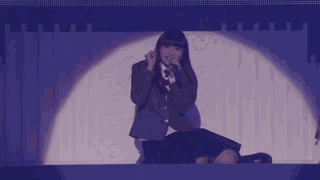 a girl in a school uniform singing into a microphone on a stage