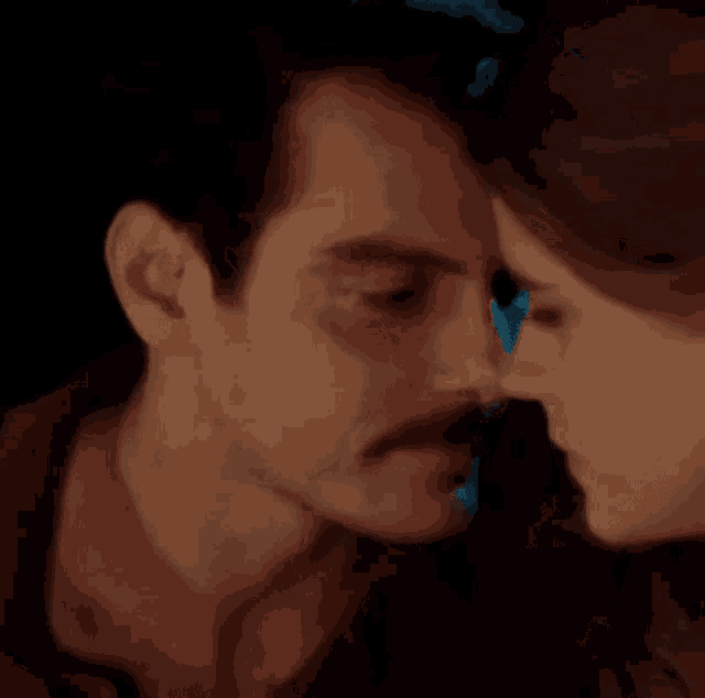 a man and a woman are touching their noses in a close up .
