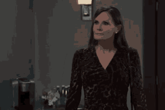 a woman in a leopard print dress is standing in a hallway looking at the camera .