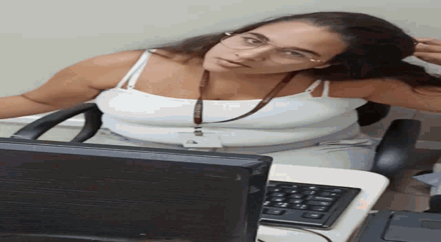 a woman wearing glasses sits at a desk with a lanyard around her neck that says " secretaria "