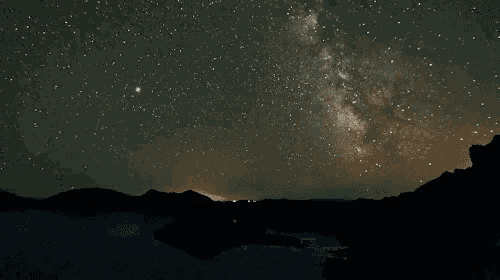 the milky way is visible in the night sky over a lake