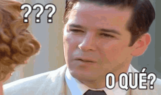 a man in a suit and tie is looking at a woman and says " o que "