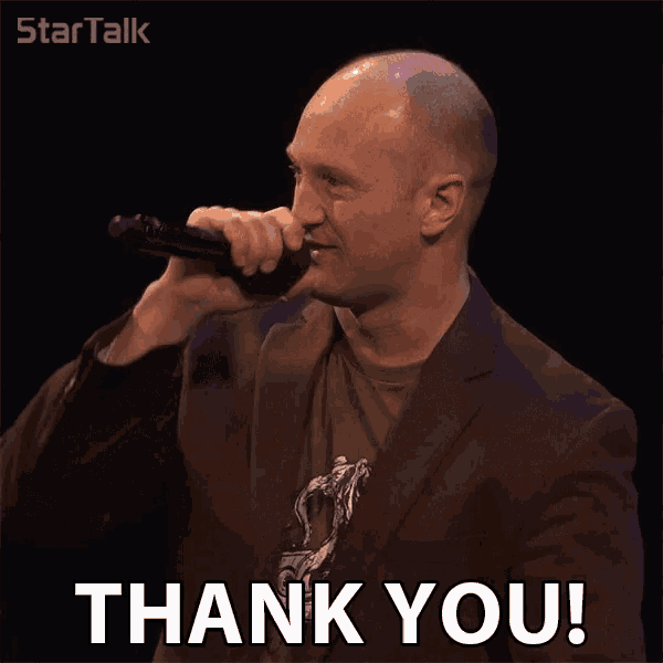 a man in a suit says thank you in front of a black background