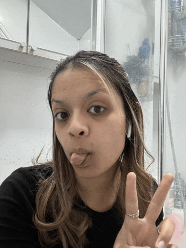 a woman making a funny face with her tongue out and a peace sign