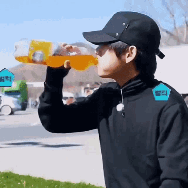 a man wearing a black hat drinks from a bottle
