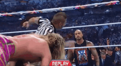 two men are wrestling in a ring with a replay sign in the corner .