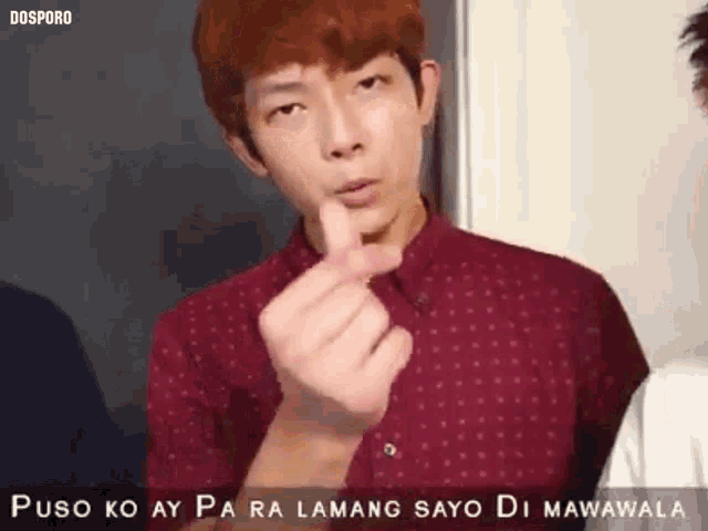 a man in a red shirt is making a heart shape with his hands .