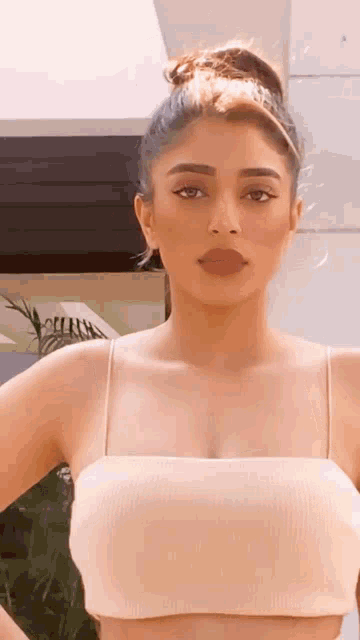 a woman is wearing a crop top and a bun .