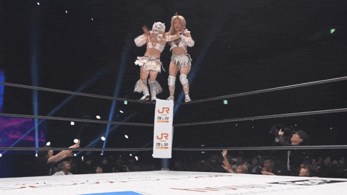 a woman is doing a flip in a wrestling ring with a sign that says ' a ' on it