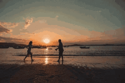 a couple walking on the beach at sunset