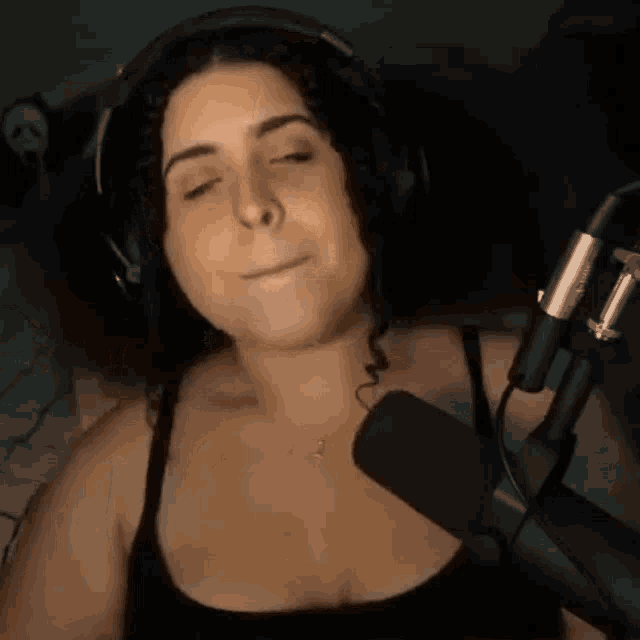 a woman wearing headphones is standing in front of a microphone .