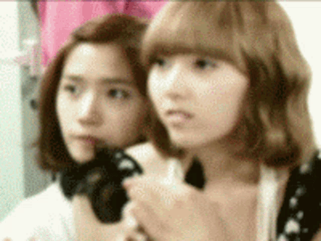 two girls are standing next to each other and one has a camera in her hand