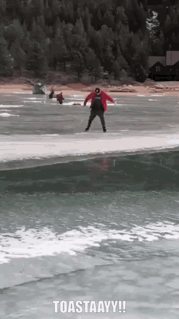 a man in a red jacket is jumping into a lake