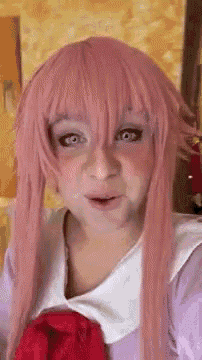a woman wearing a pink wig and a purple dress is making a funny face .