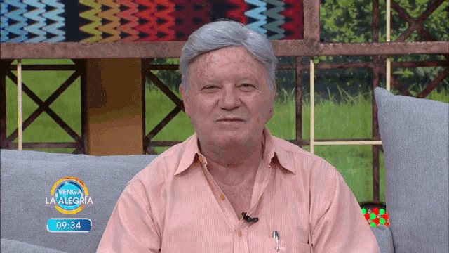 a man sits on a couch in front of a sign that says la alegria