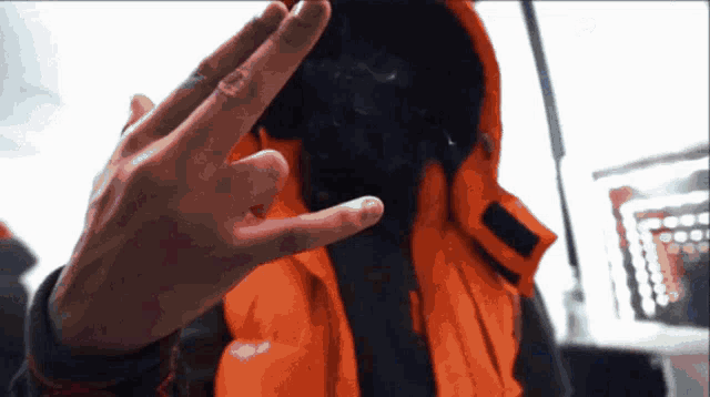 a person wearing an orange vest is making a peace sign with their hand