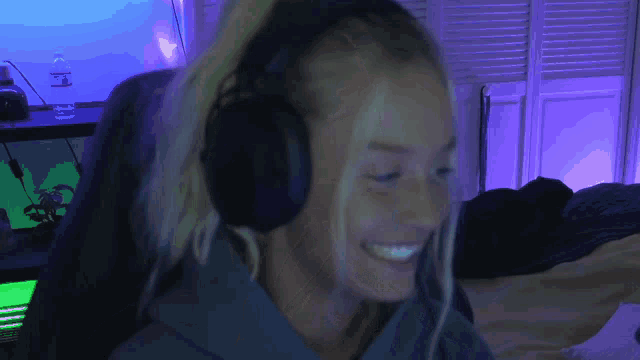 a woman wearing headphones is smiling in front of a computer screen