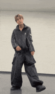 a man in a black jacket and black pants is dancing in a room