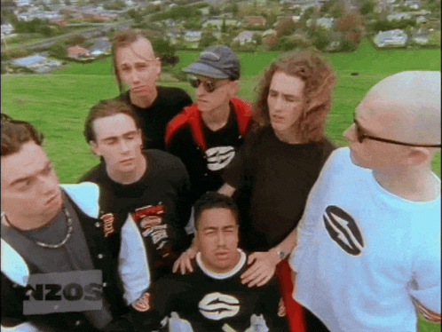 a group of men are standing in a field and one of them has a shirt that says rizos