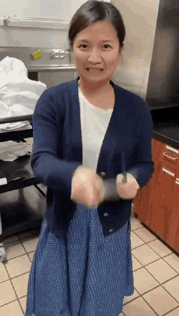 a woman wearing a blue cardigan and a blue skirt is holding a knife