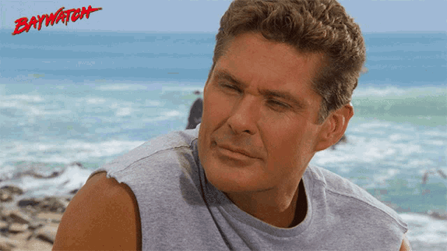 a man wearing a grey shirt with the word baywatch on it