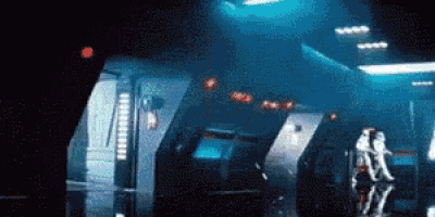 a couple of people are standing in a dark room with a blue light shining on them .