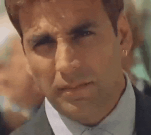 a close up of a man in a suit and tie with earrings on his ear .