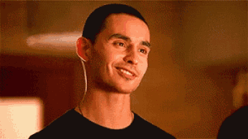 a man wearing headphones is smiling and looking at the camera while wearing a black shirt .