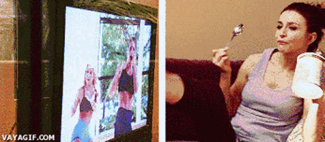 a woman is holding a spoon in front of a tv screen that says vayagif.com on it